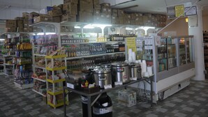 A kitchen area with various cooking appliances, storage shelves, and boxed items. - Himawari Hotel (Saipan)