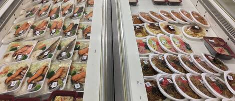 Vitrina refrigerada con diversos alimentos, como mariscos y comidas preparadas.