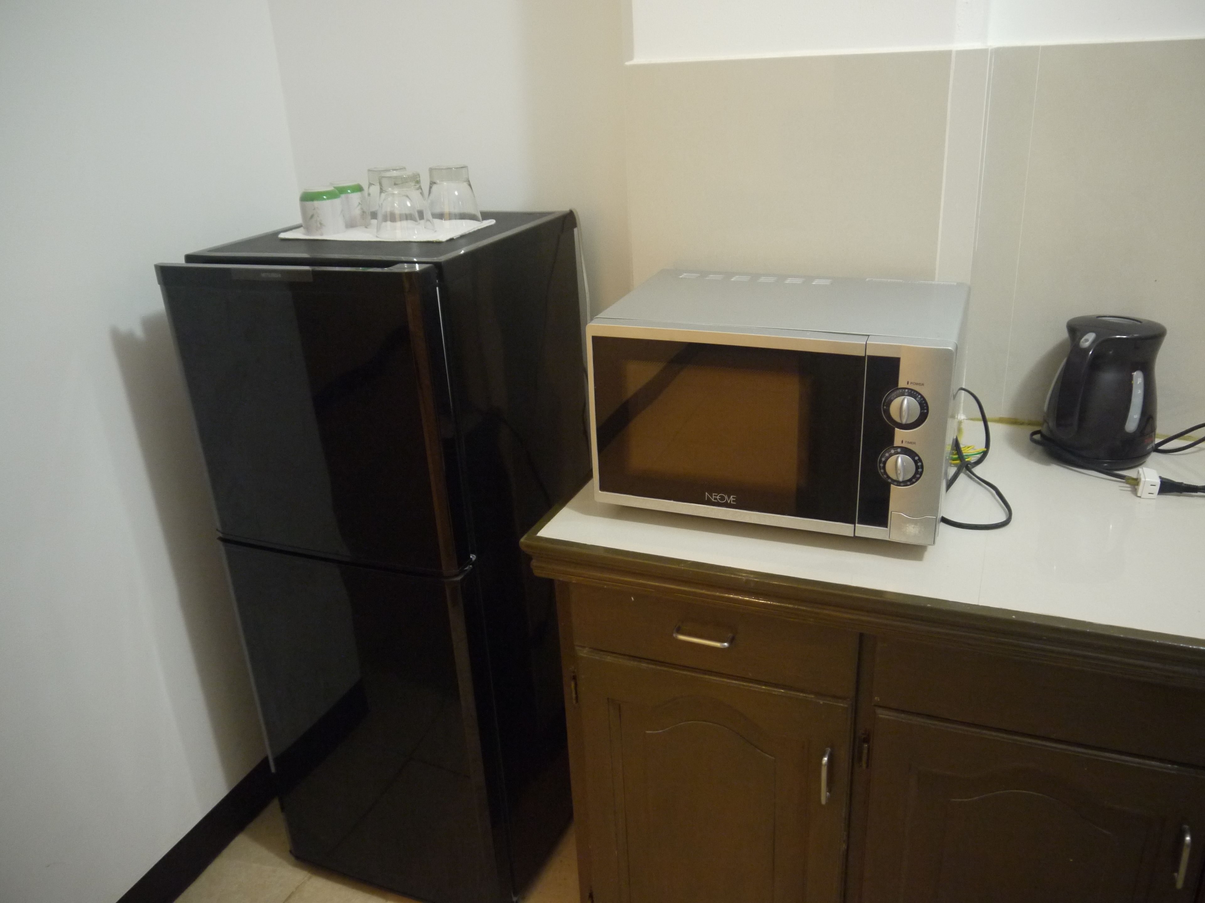 A compact kitchen with a black refrigerator, a microwave, and a coffee maker on the countertop.