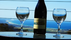 A bottle of 2006 Pinot Noir Tasmanian wine and two wine glasses on a table with a scenic view. - Lumera Chalets (St Marys)