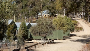 A campground with several green-roofed cabins, a dirt road, and surrounding trees. - Lumera Chalets (St Marys)
