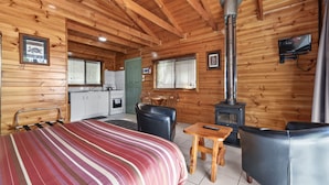A cozy cabin with a bed, a fireplace, a dining area, and a kitchen. - Lumera Chalets (St Marys)