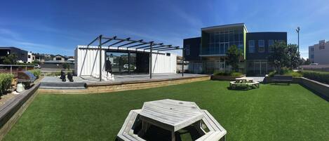 A courtyard with a stage, outdoor seating, and a building with large windows.