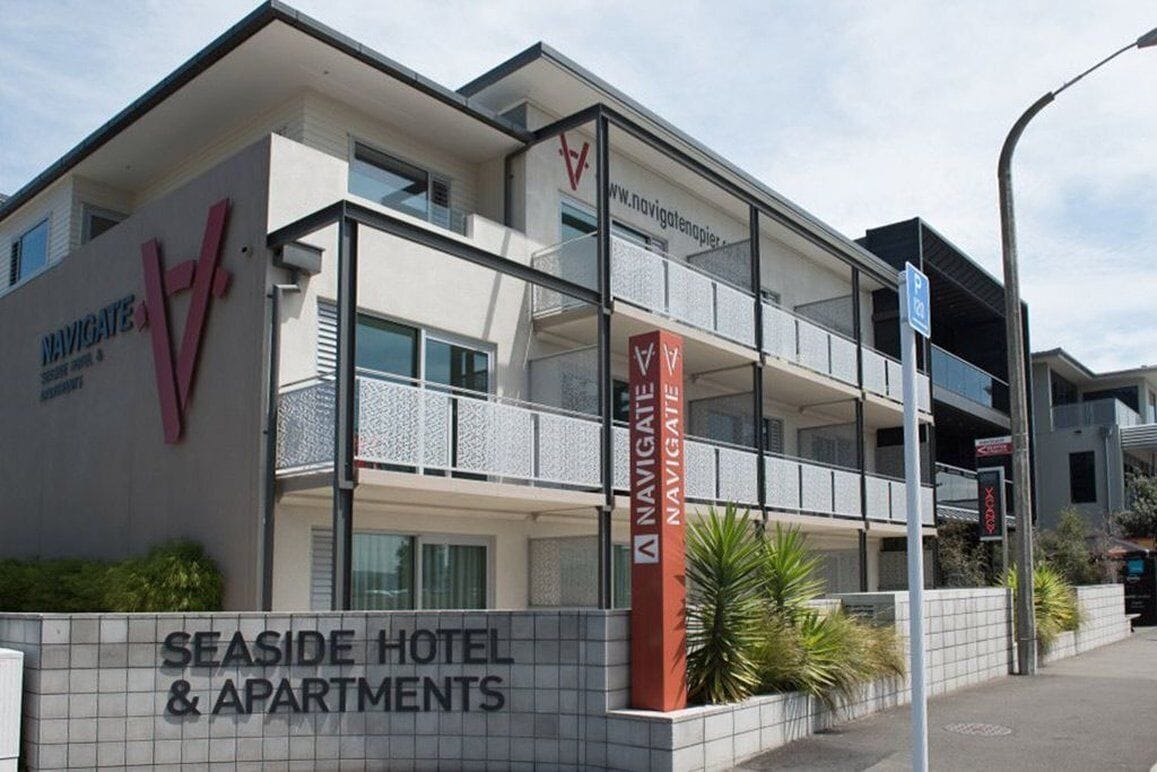 A multi-story hotel with balconies, a prominent 'Navigare' sign, and a sign for 'Seaside Hotel & Apartments'.