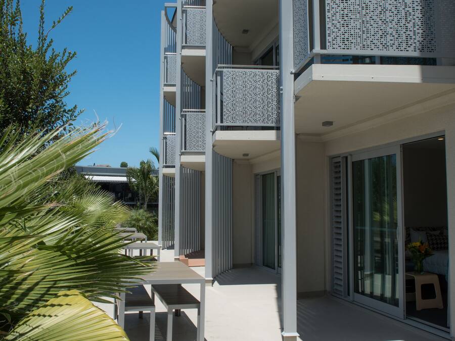 Un edificio moderno con varios balcones, una zona de estar exterior techada y vistas al cielo.