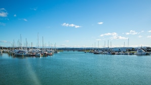 A marina with multiple boats docked, calm water, and a clear sky.