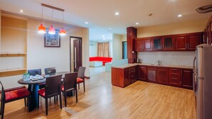 A modern kitchen with wooden cabinets, a dining area with a table and chairs, and a red accent wall.