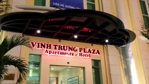 The exterior of Vinh Trung Plaza Hotel with a prominent sign and a colorful poster above the entrance.