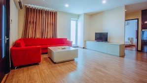 A modern living room with a red sofa, a white coffee table, and a TV on a white cabinet.