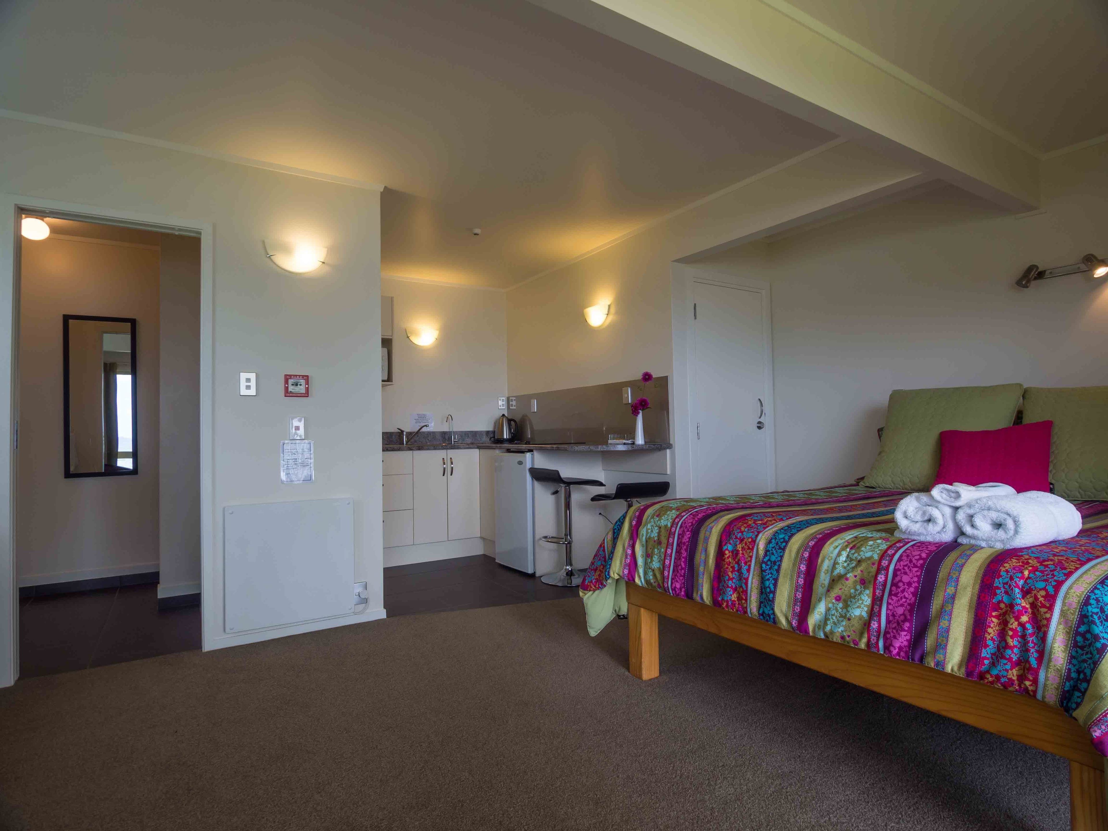 Ein Schlafzimmer mit einem Bett, einer kleinen Küchenzeile und einem Badezimmer.