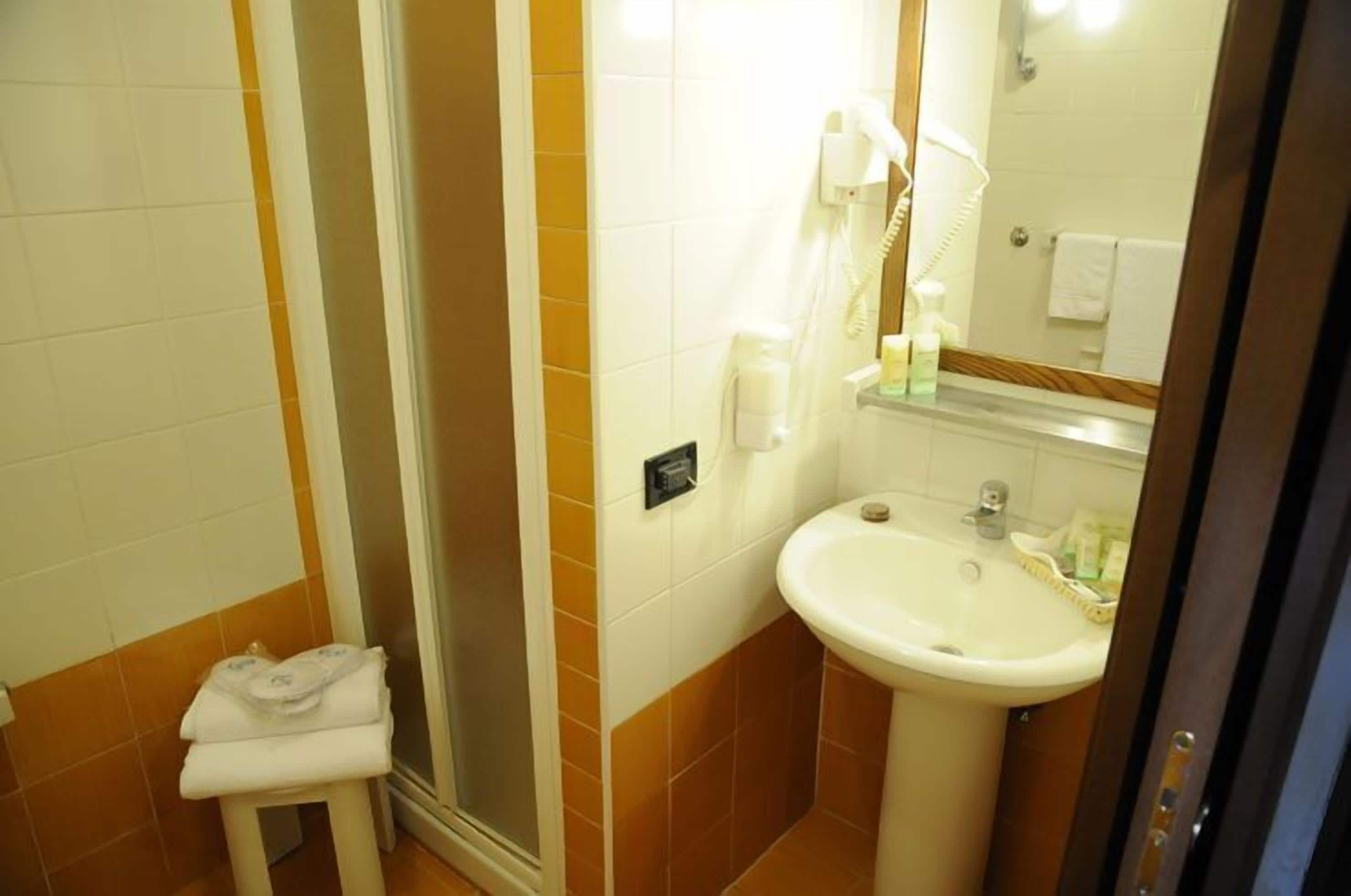Une salle de bain avec une douche, un lavabo et un porte-serviettes.