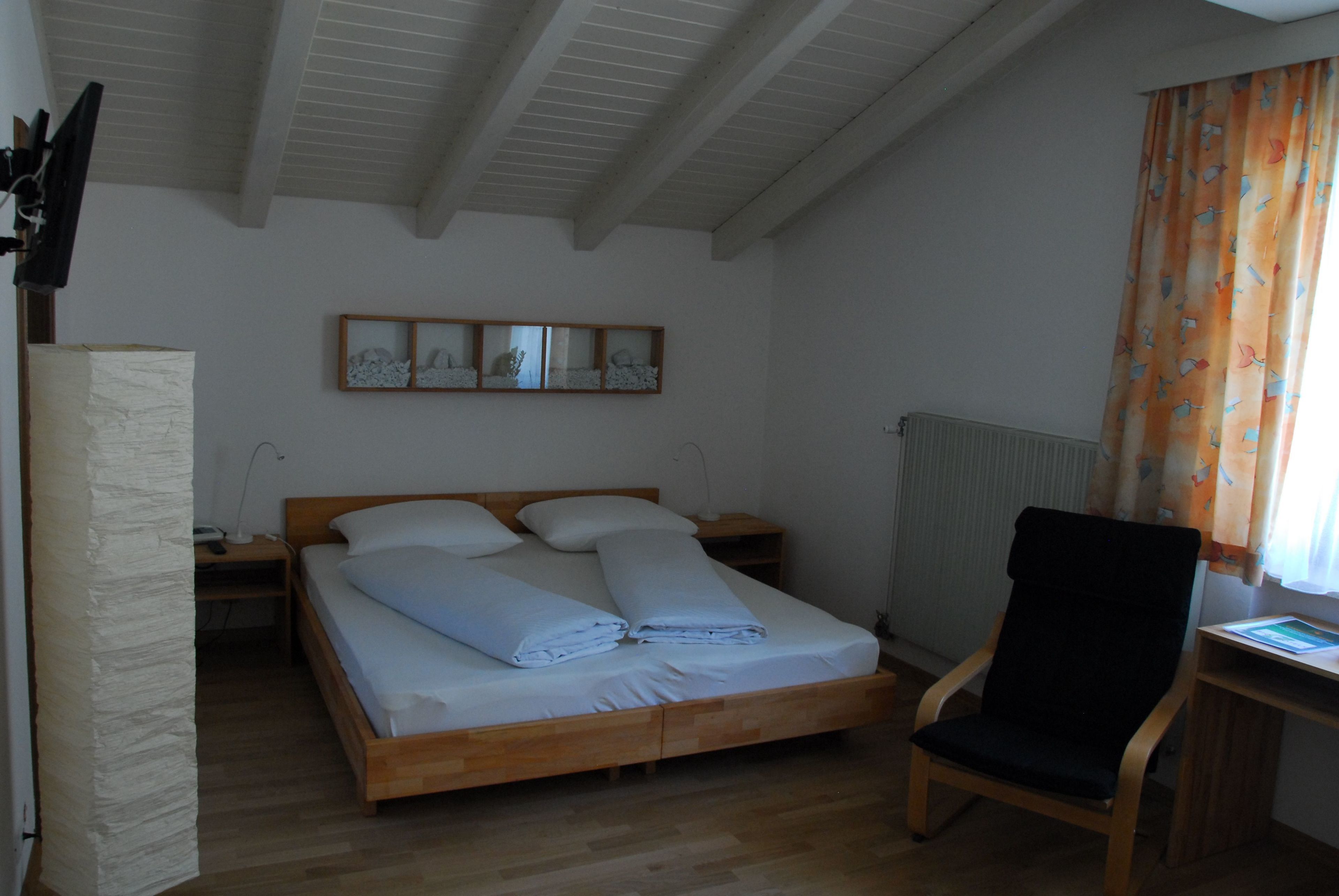 Une chambre à coucher avec un lit en bois, une chaise, un bureau et un radiateur.