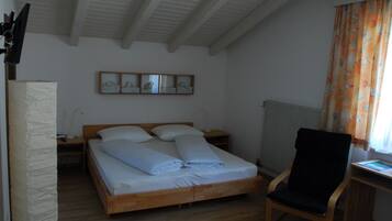Une chambre à coucher avec un lit en bois, une chaise, un bureau et un radiateur.
