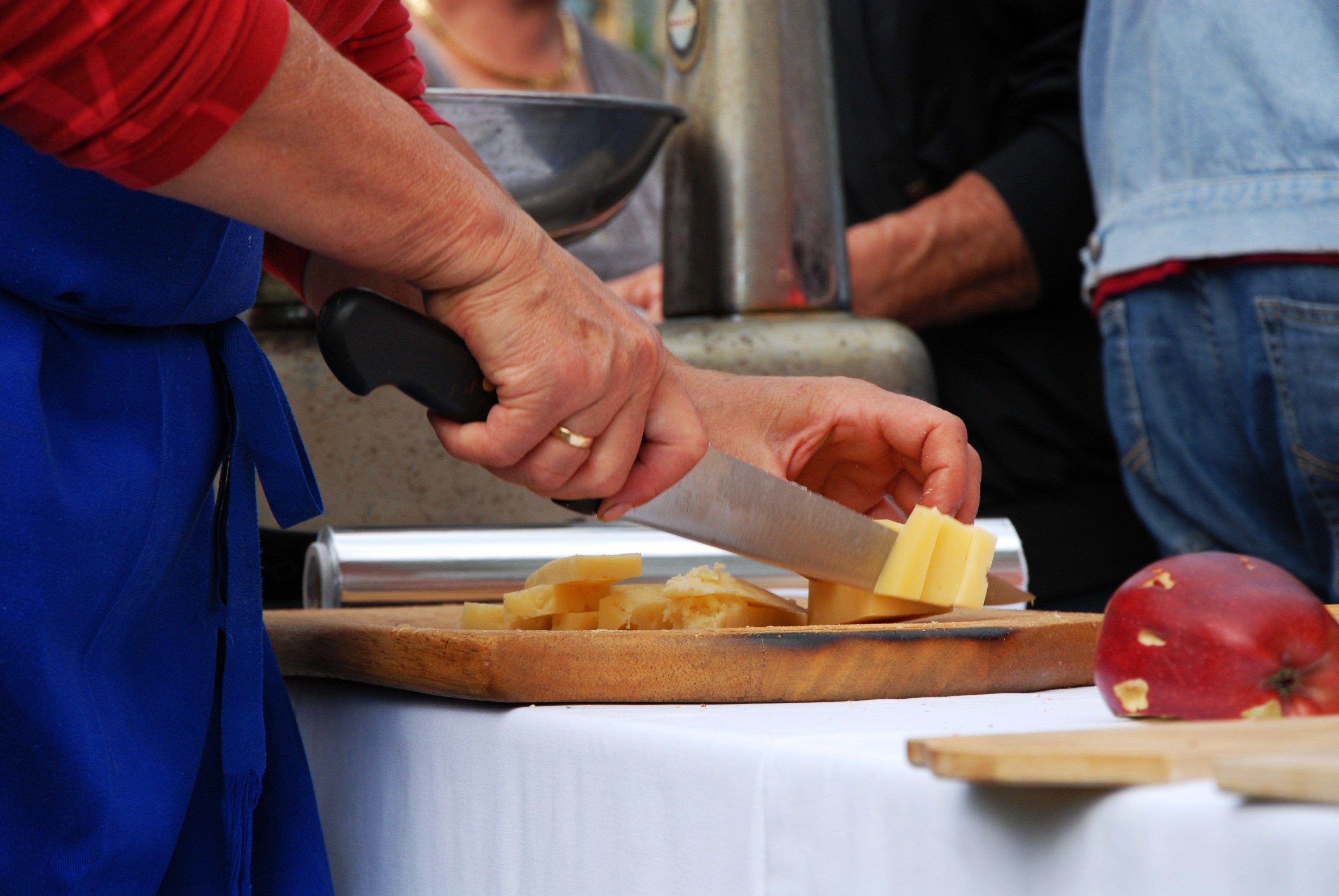 Una persona cortando queso sobre una tabla de madera.
