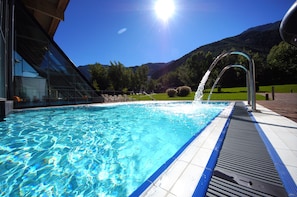 A swimming pool with clear blue water, a metal handrail, and a view of mountains in the background.