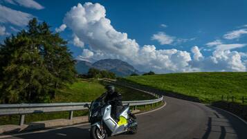 Un motociclista en una carretera sinuosa con una montaña al fondo.