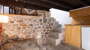 Une cuisine rustique avec des murs en pierre, des armoires en bois et un évier encastré.