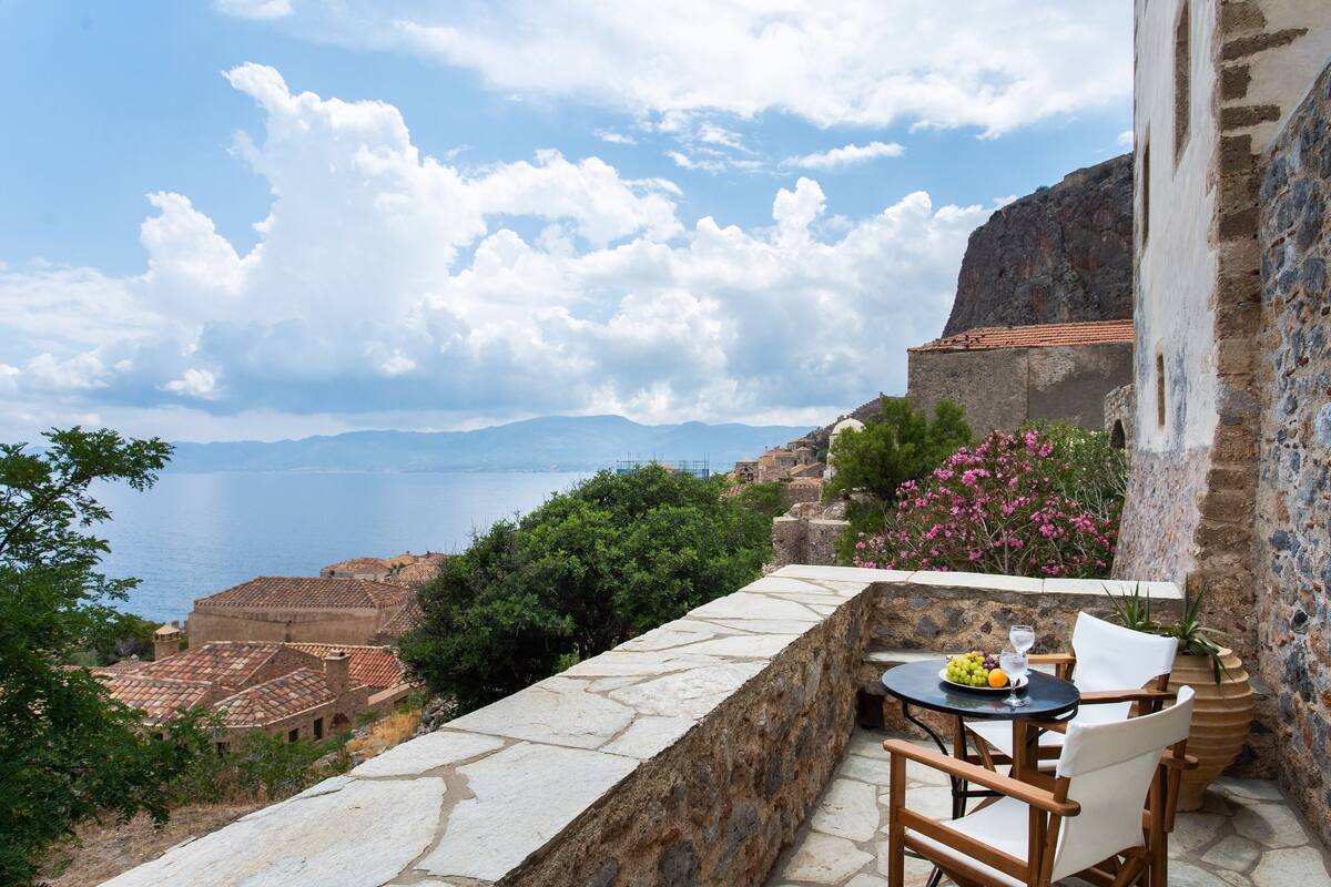 Terraza de piedra con mesa y sillas con vistas al mar.