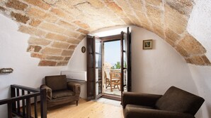 Une pièce mansardée chaleureuse, avec un plancher en bois, un canapé marron, une chaise en bois et un escalier menant à un espace extérieur.