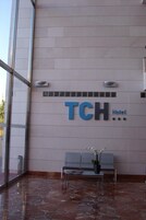 Área de recepção do hotel TCH com piso de mármore, balcão de atendimento e espaço para acomodação.