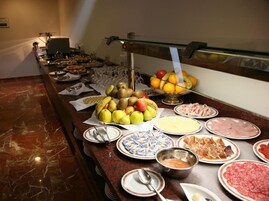 Buffet com diversas opções de comida, incluindo frutas, carnes e sobremesas.
