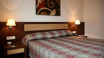 Habitación de hotel con cama, dos mesitas de noche, una obra de arte en la pared y dos lámparas de pared.
