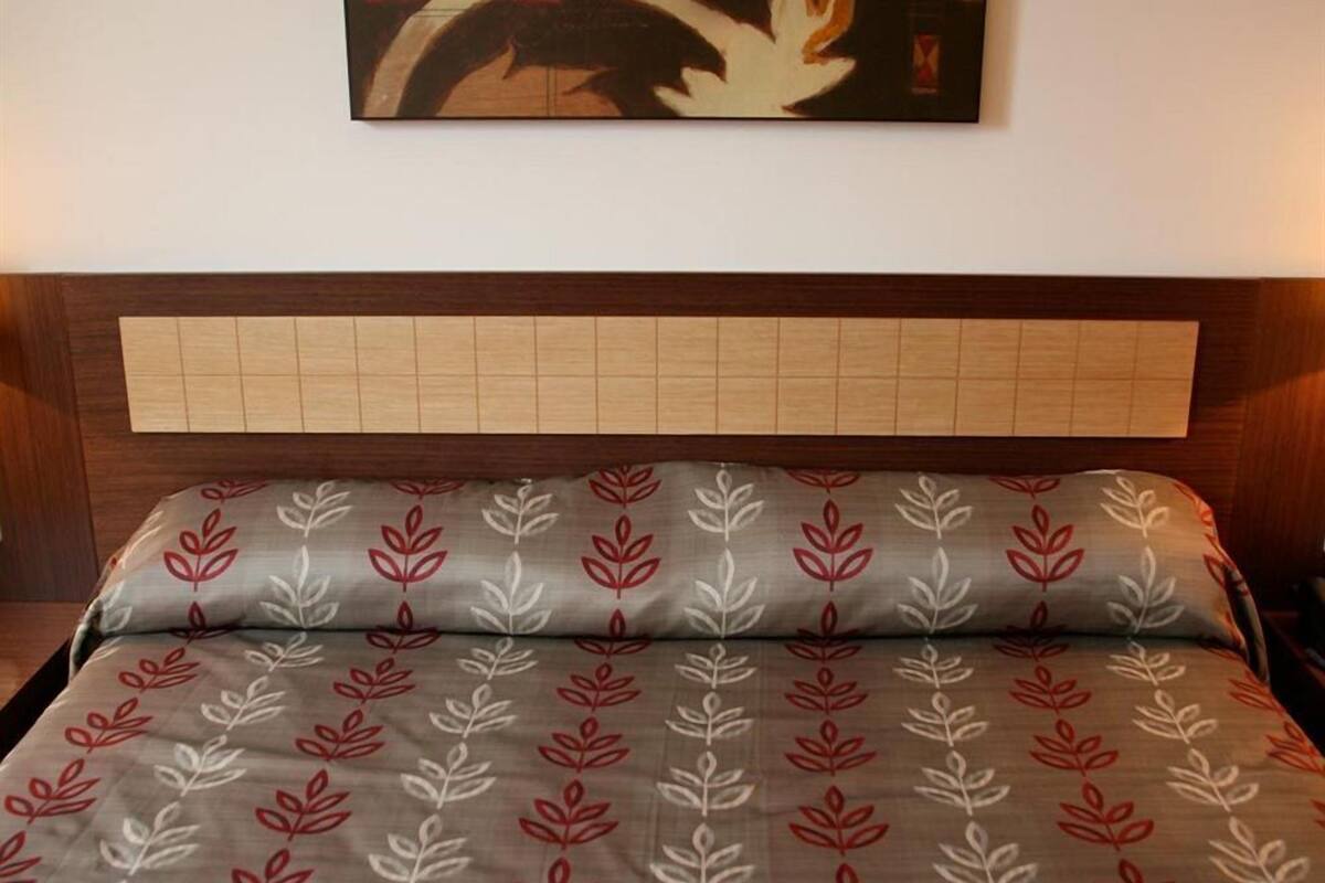 Una cama con cabecera de diseño calado y almohada con estampado de hojas.