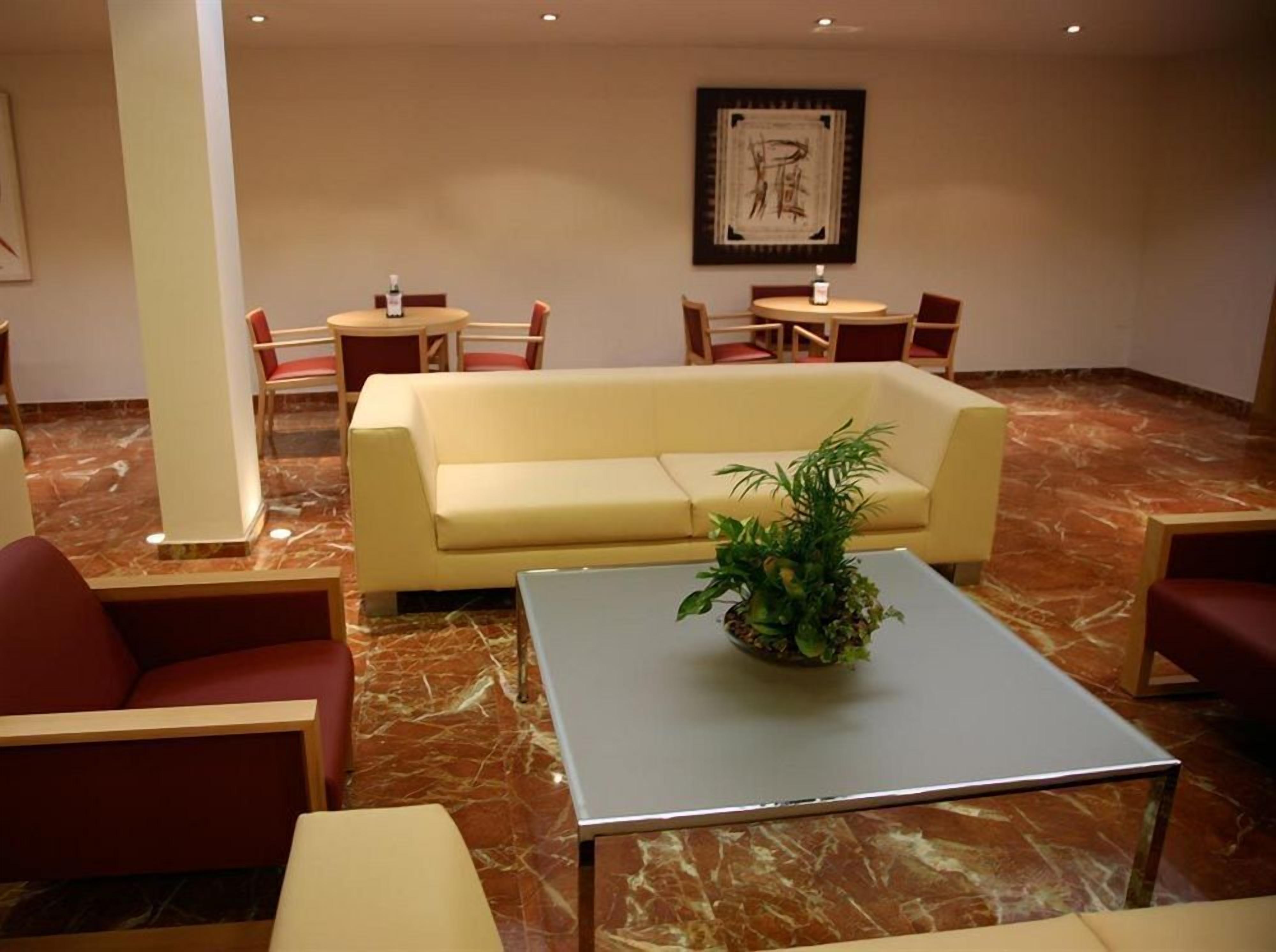 A lobby with a sofa, chairs, a small table, and a decorative plant.