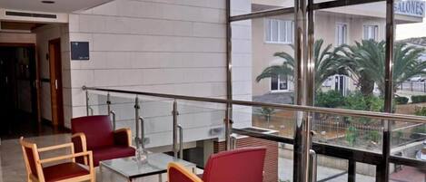 A hotel lobby with a glass railing, red chairs, and a view of the outside.