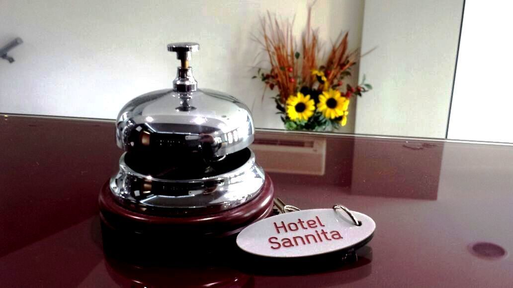 A hotel bell with a keychain sign reading "Hotel Sannita" on a reflective surface.