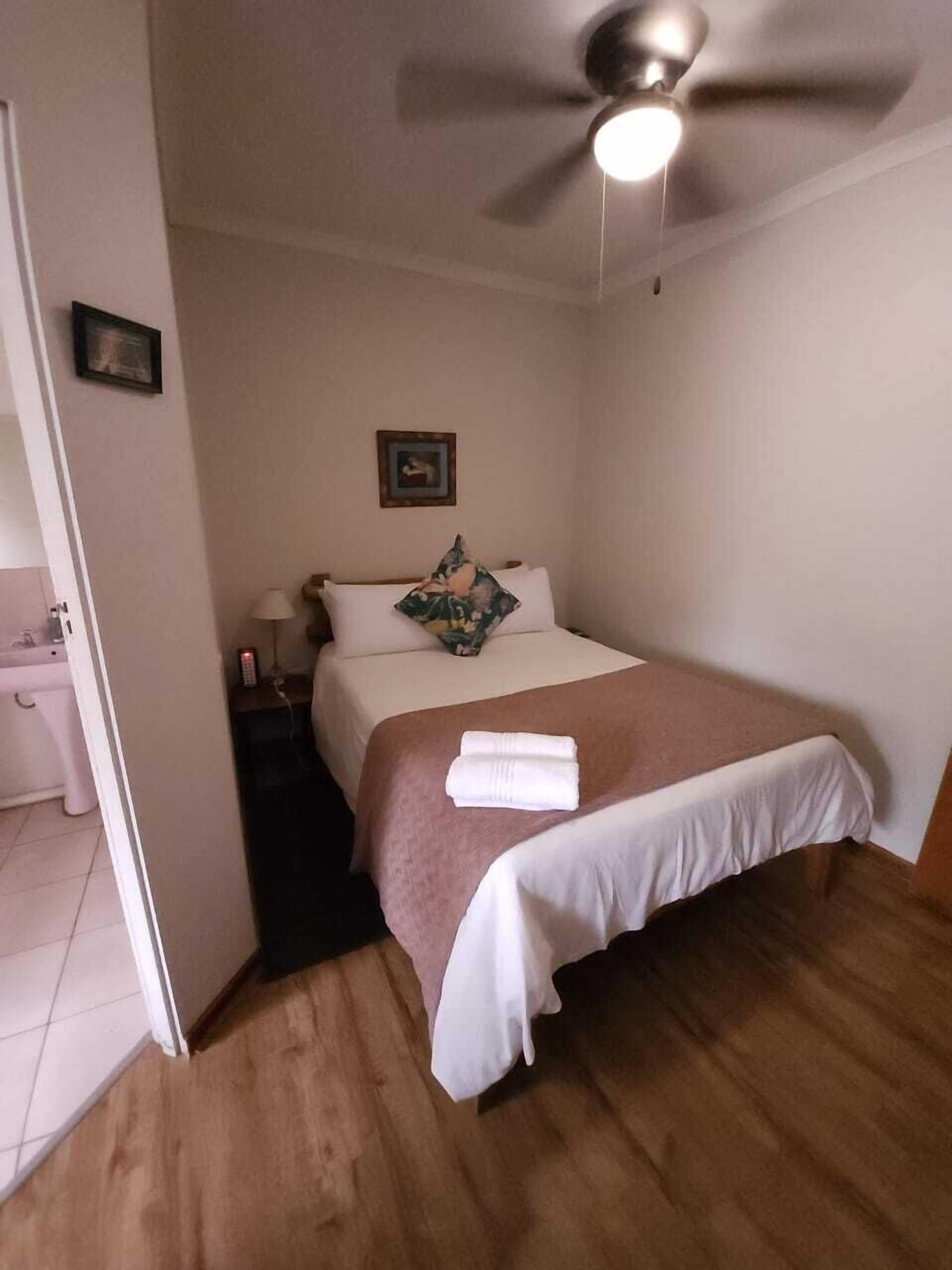 A neatly made bed with a white and pink bedspread, a pillow, and a folded towel on the side.