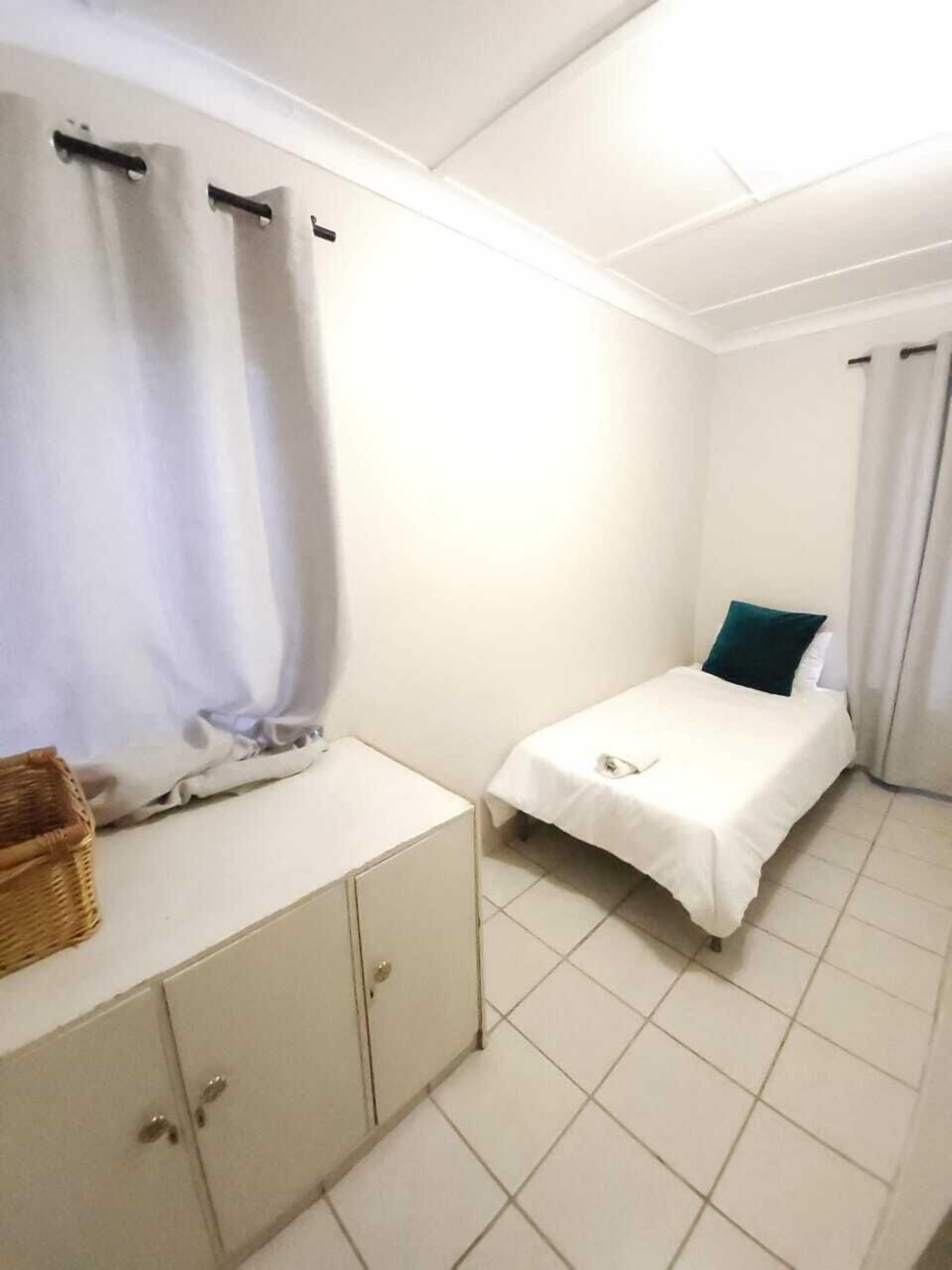 Une petite chambre propre, avec un lit, une table de chevet et une armoire.