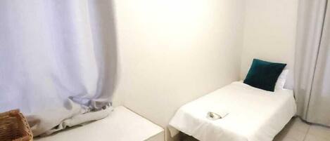 A small, clean room with a bed, a bedside table, and a wardrobe.