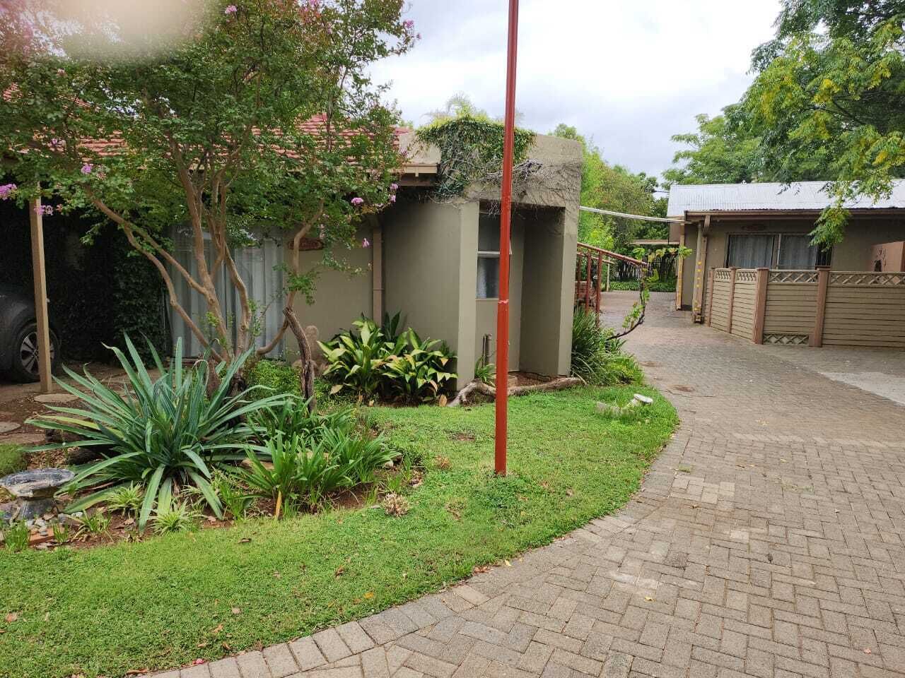 Un sendero pavimentado que conduce a un edificio con un pequeño jardín y un patio cercado.