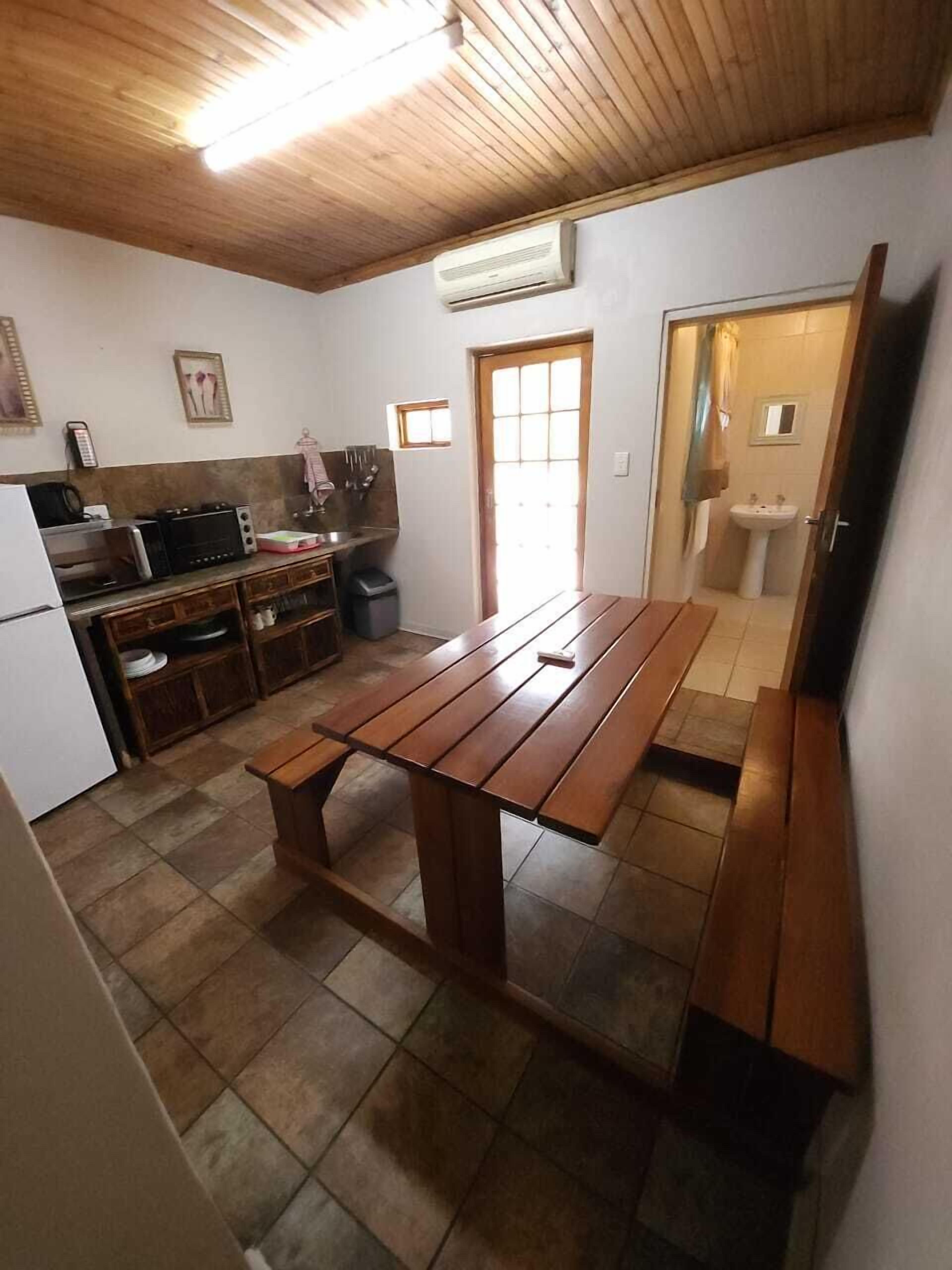 Una cucina compatta con un tavolo di legno e panche, un frigorifero, un forno a microonde e un lavandino.