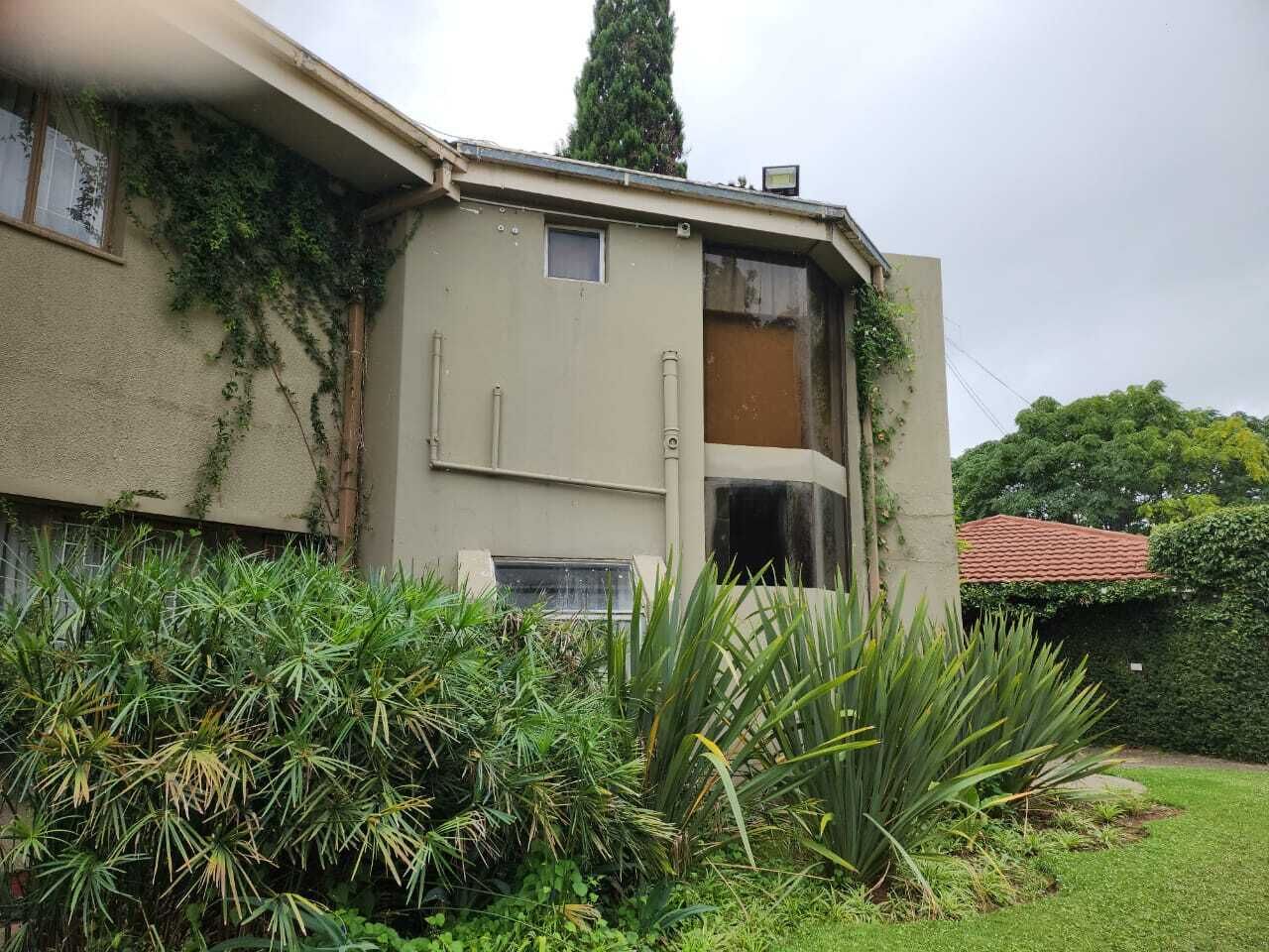 Un edificio con fachada color beige, una ventana pequeña y un caño de agua visible.