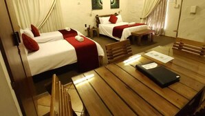 A hotel room with two beds, a wooden table, and a bench. - Rusplek Guesthouse and Conference Centre (Bloemfontein)