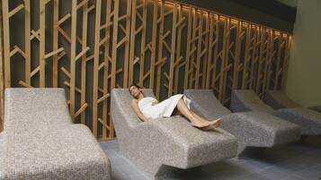 A spa room with a wooden wall and three cushioned chairs.