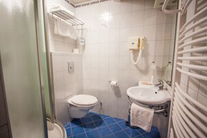 Casa de banho com sanita, lavatório e porta-toalhas.