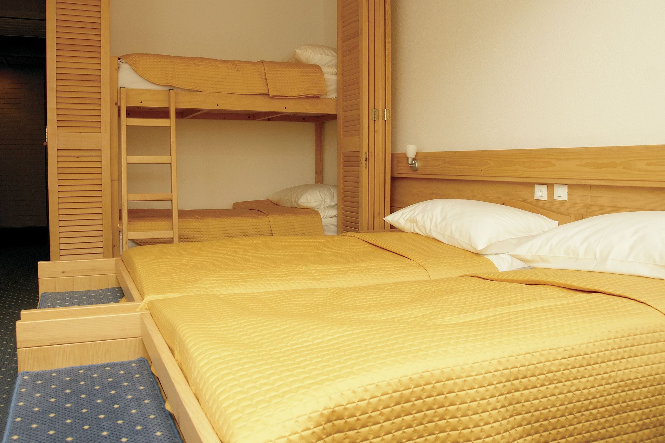 Habitación con literas, cabecera de madera, escalera y cajón extraíble.
