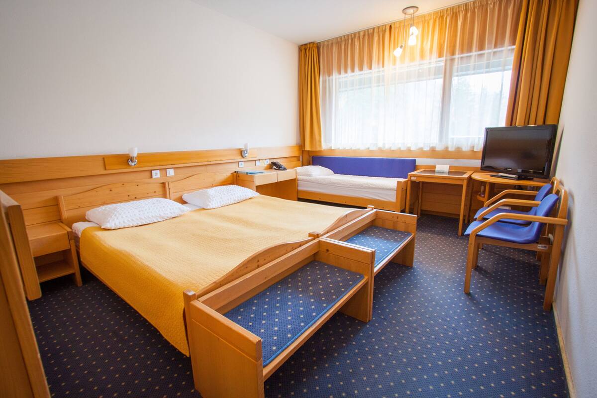 Ein Hotelzimmer mit einem Bett, einem Schreibtisch, einem Sessel und einem Fernseher.