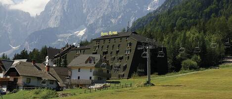 A hotel with a ski lift and mountainous backdrop.