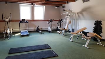 Une salle de sport équipée de divers appareils d’exercice, notamment des tapis de course, des vélos d’appartement et des appareils de musculation.