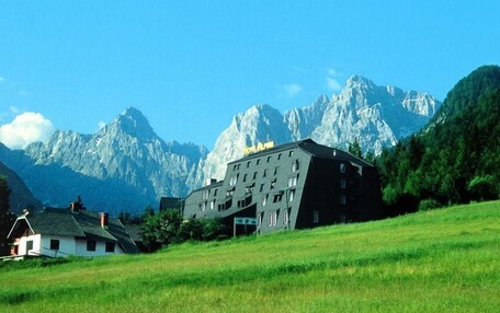 A hotel with a modern design, set against a backdrop of mountains.