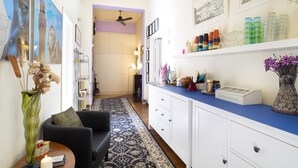 A narrow hallway with a black sofa, a patterned rug, and a white cabinet with various items on top. - 1900 Artevita (Florence)