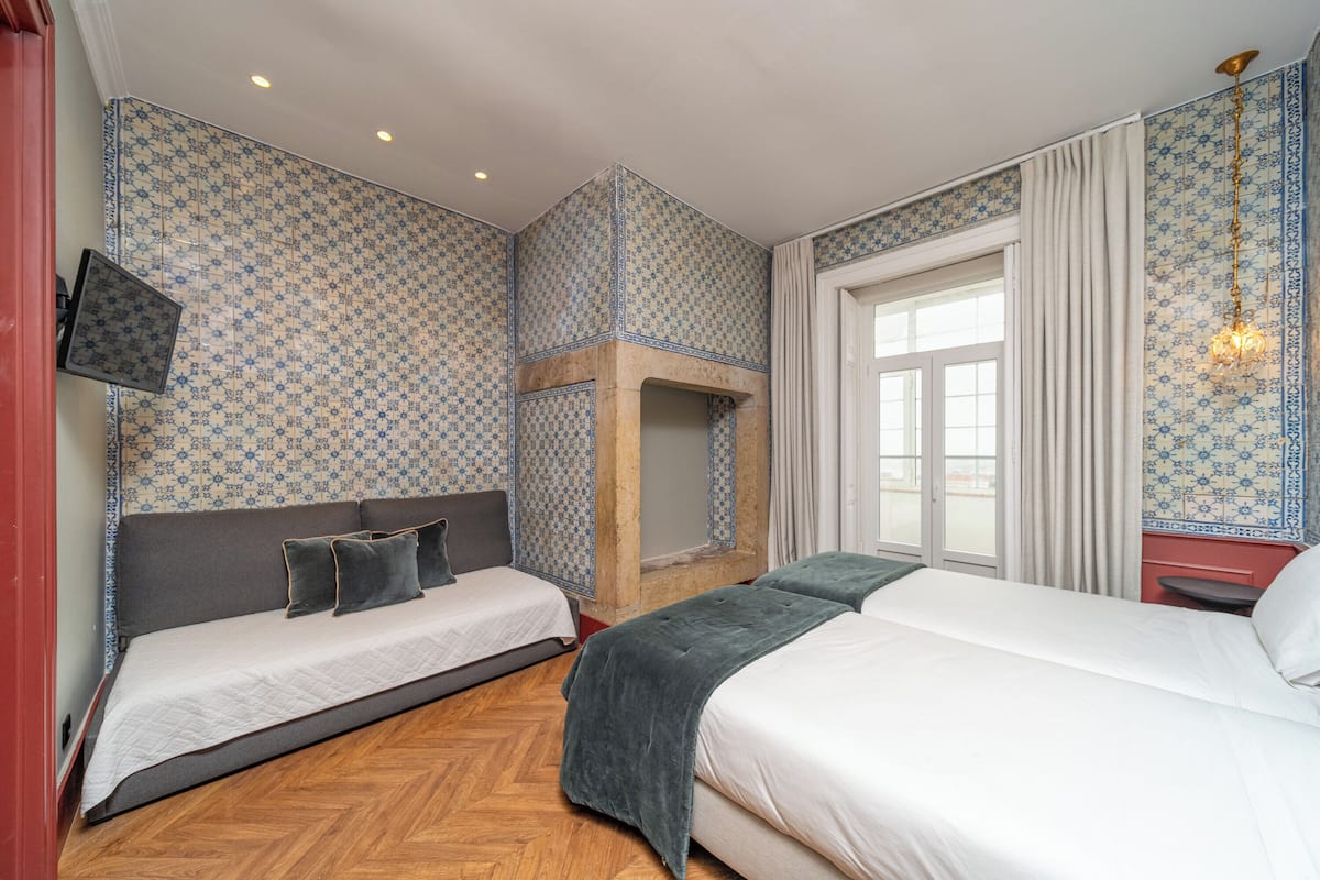 A hotel room with two beds, a fireplace, a TV, and a large window.