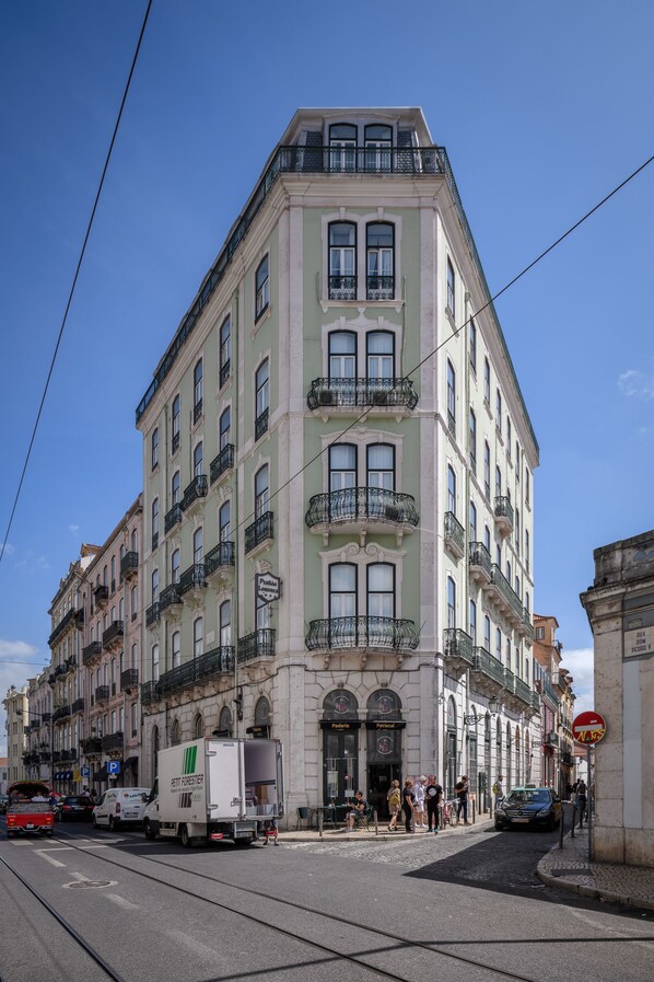 A multi-story building with balconies, a tram, and a street scene. - Pensão Londres (Lisbon)