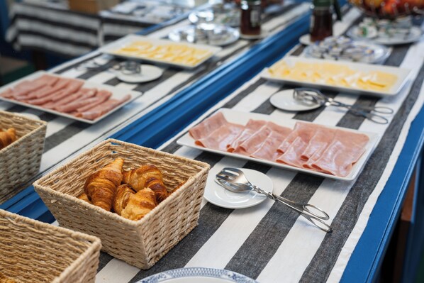 A buffet table with various food items including pastries, meats, and cheeses. - Pensão Londres (Lisbon)