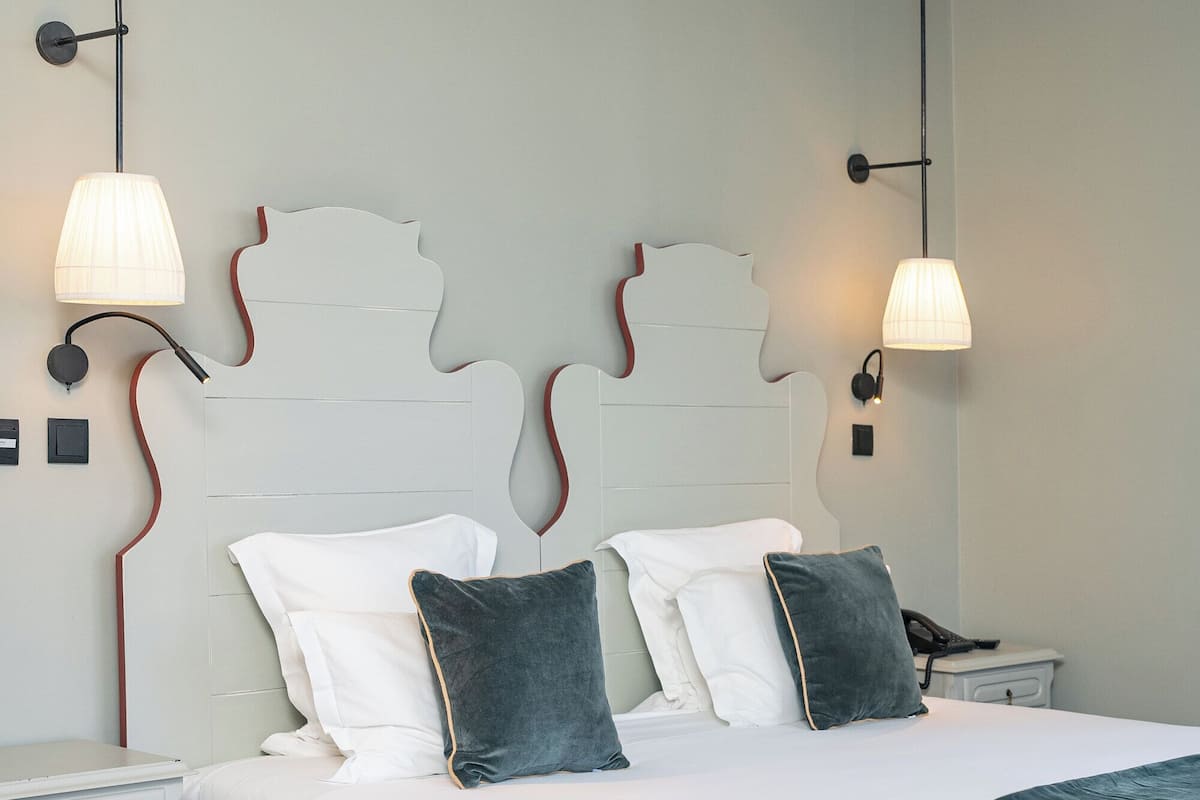 A neatly arranged bedroom with a bed, bedside tables, and wall-mounted lamps.