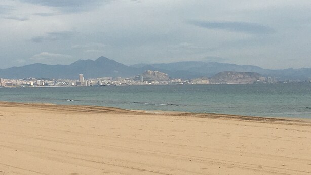 A beach with a cityscape in the background. - Hostal Meseguer (Elche)